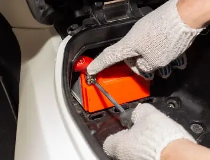 car mechanic removes battery from motorbike battery repair replacement 1